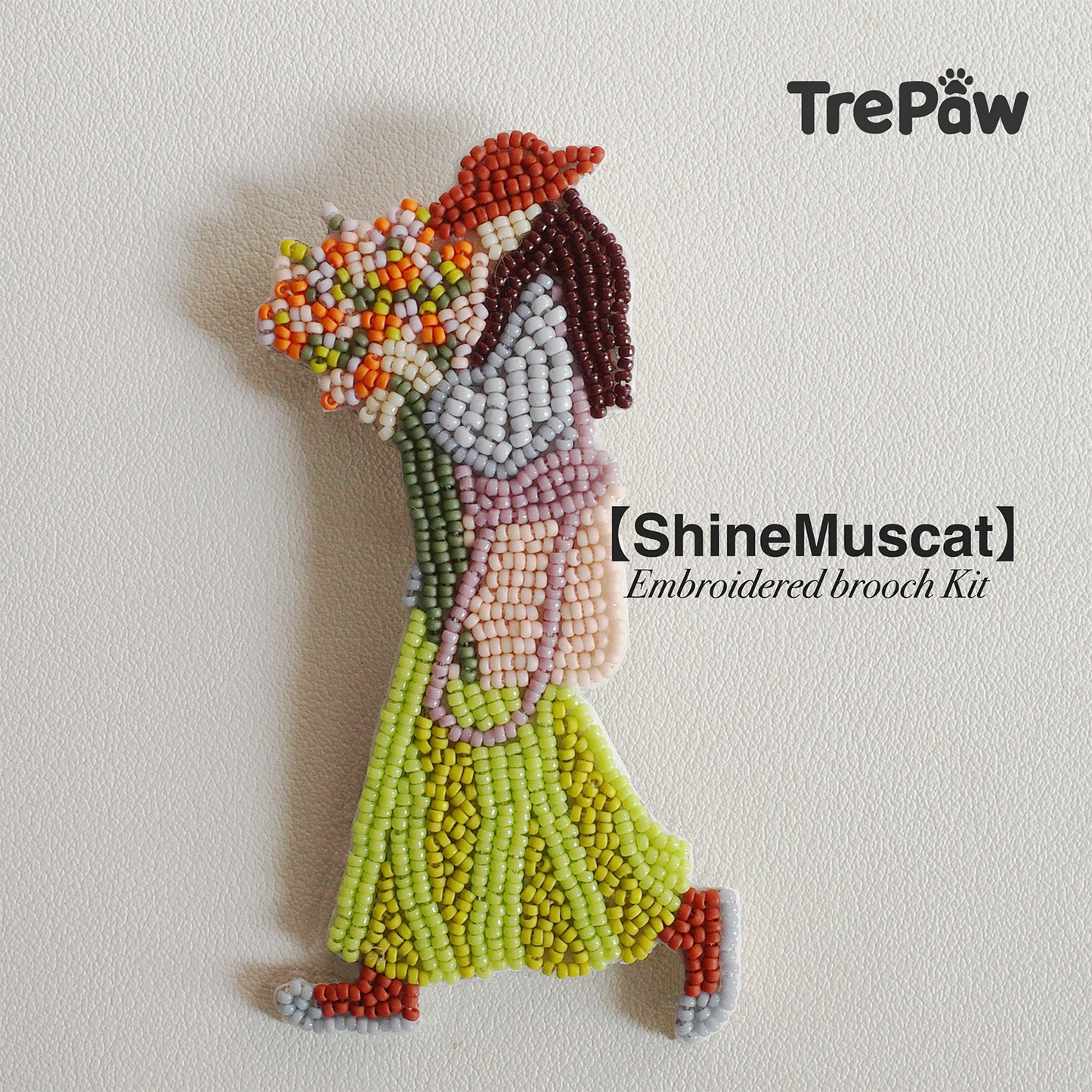 Shine Muscat bead embroidery kit - girl in green dress and dark orange hat, adjusting bouquet while walking, finished beaded pendant