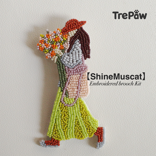 Shine Muscat bead embroidery kit - girl in green dress and dark orange hat, adjusting bouquet while walking, finished beaded pendant