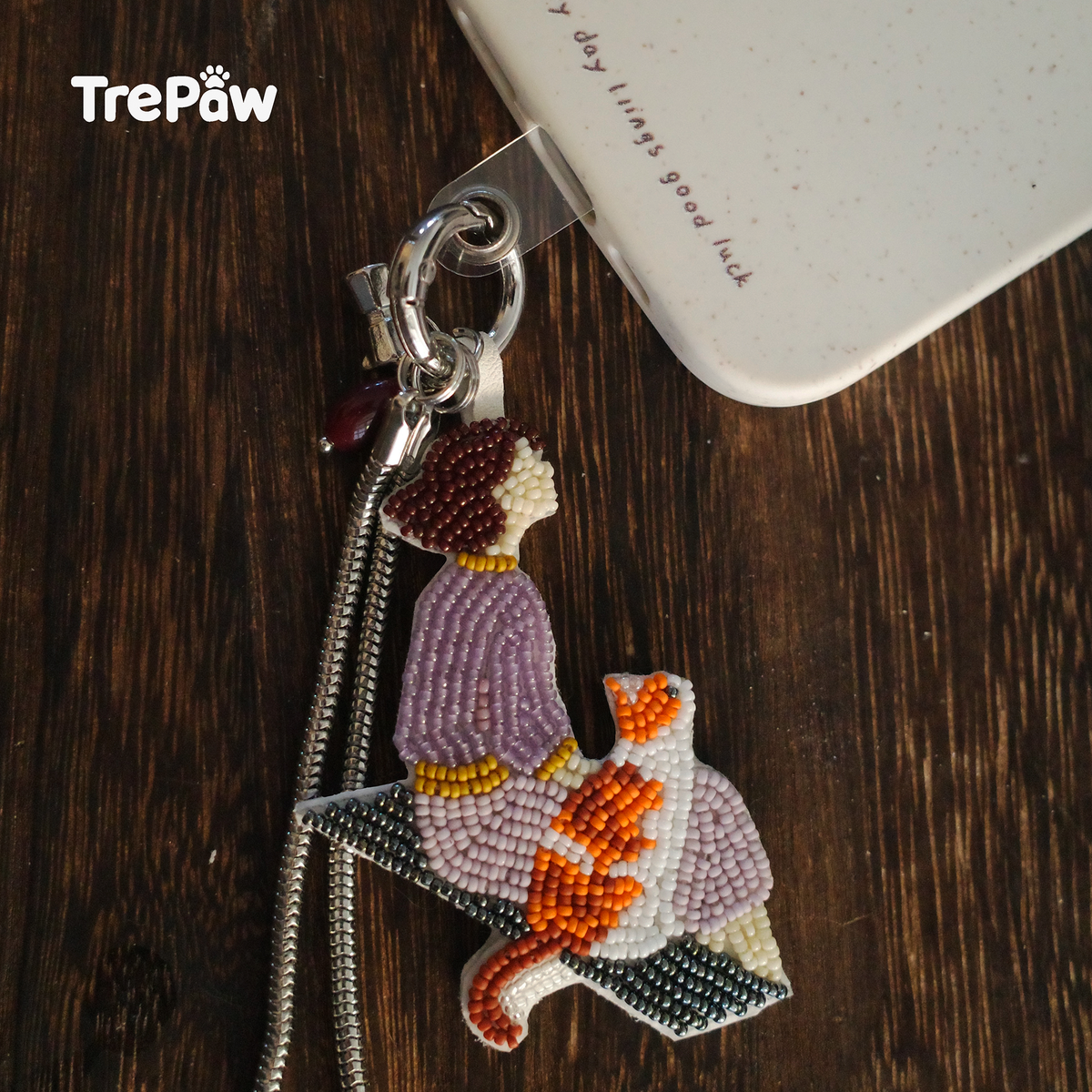 Companion handmade cat bead embroidery charm attached to a phone case